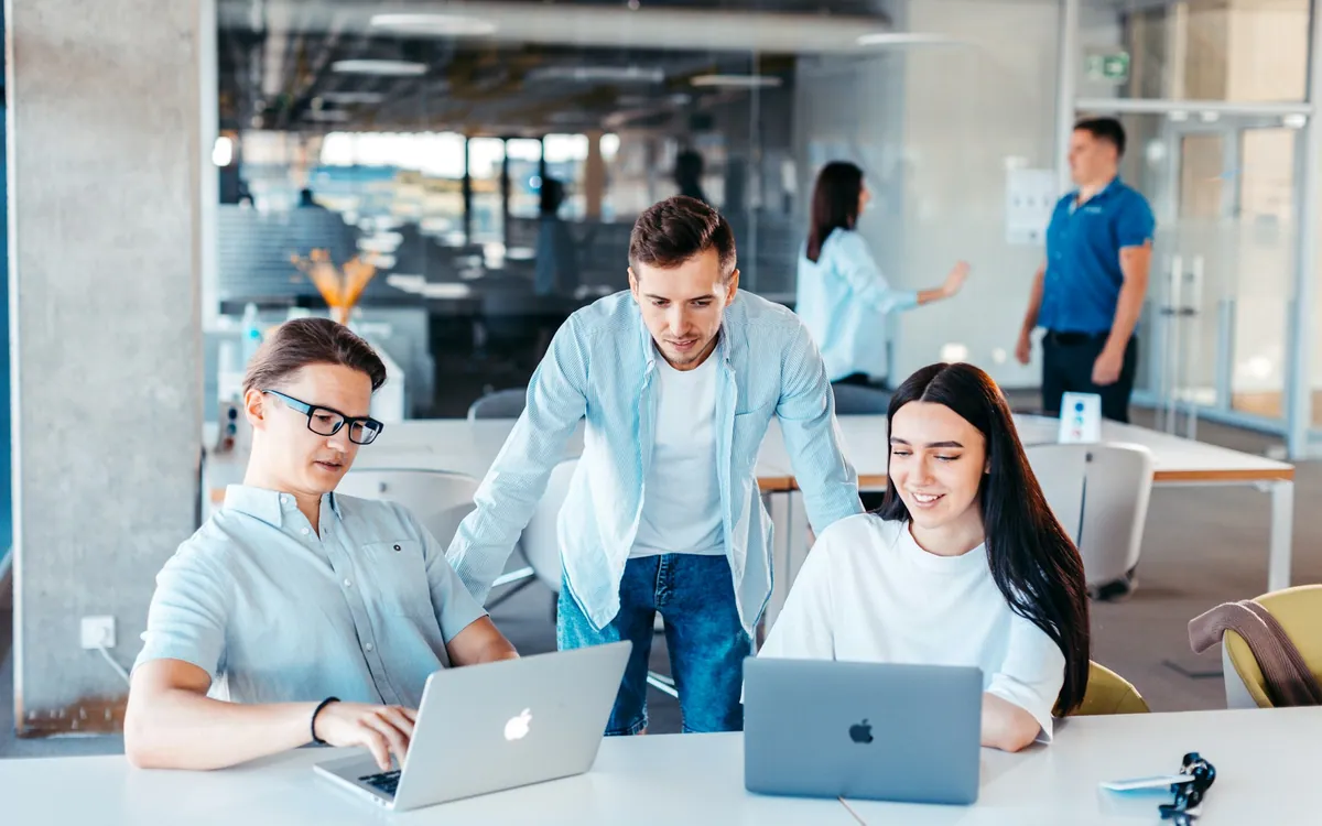 Equipe de desenvolvimento reunida em volta de uma mesa com notebooks