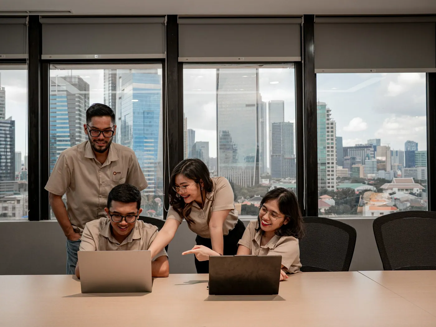 Equipe reunida em volta de notebooks numa sala com vista para a cidade